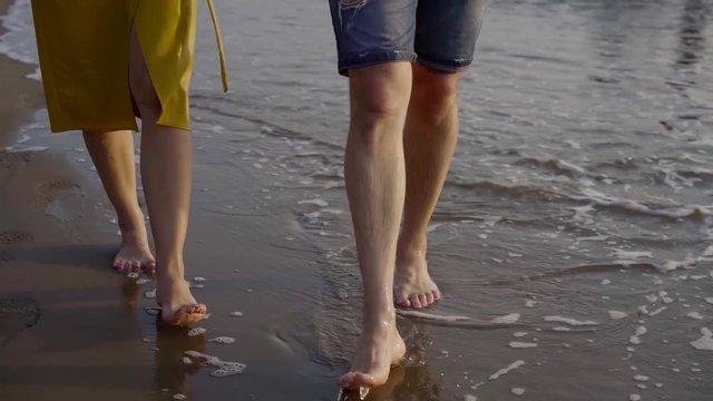 couple of lovers walking on the beach close-up. Cover your legs and legs . Romantic woman and man on vacation summer vacation