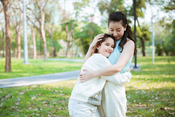 Beautiful mother hug little daughter in the park