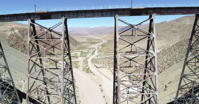 Aerial flying over old train metal bridge, in desertic mountainous valley. Tren de las nubes, train of the clouds, San antonio de los cobres, Salta, Argentina