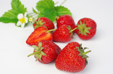 Ripe strawberries with leaves and flowers on white, close-up
