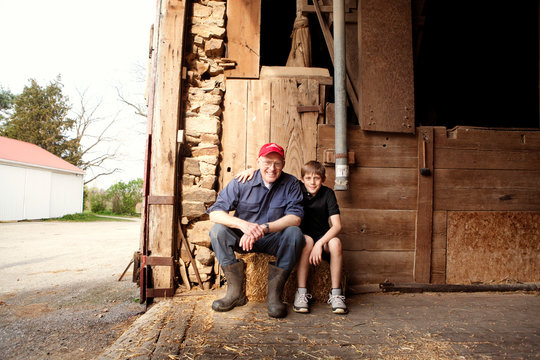 Grandfather sitting with grandson(10-11) in barn 