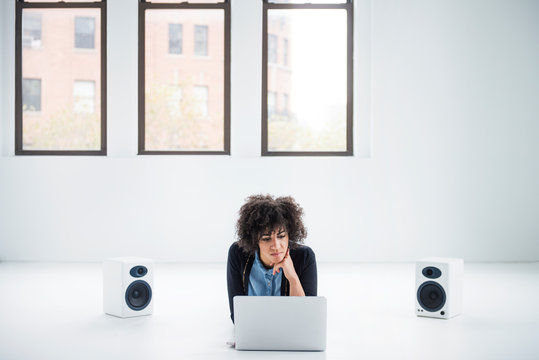 Young Woman Lying On Front, Using Macbook 