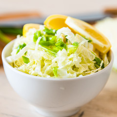 Bowl of Chinese cabbage salad with lemon and green onions - traditional Japanese vegetarian appetizer.