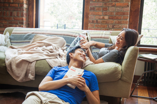 Mid adult couple relaxing in modern house interior, lying down, blanket on sofa 