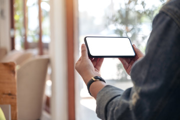 Mockup image of a woman holding black mobile phone with blank desktop screen horizontally