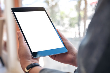 Mockup image of a woman holding black tablet pc with blank white screen while sitting in cafe