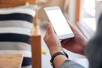 Mockup image of hands holding white mobile phone with blank screen in cafe