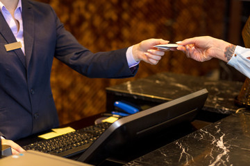 Easy transaction, woman paying with a credit card at hotel reception, close up.