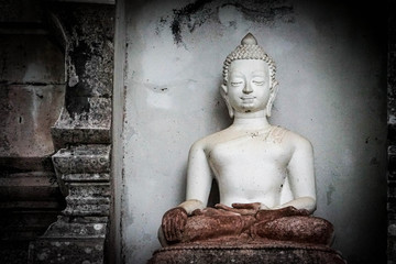 Great white Buddha statue with old background wall.