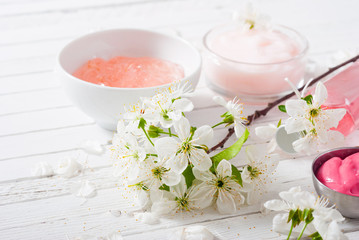 beauty products and cherry blossom on white wood table