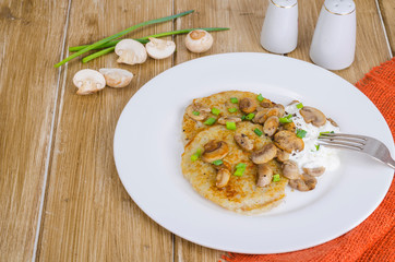 Rustic food concept. Fried potato pancakes with sauce and mushrooms on wooden table