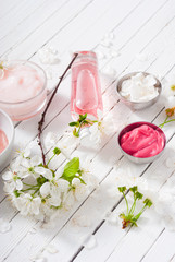 beauty products and cherry blossom on white wood table