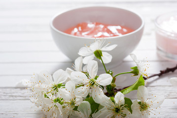 beauty products and cherry blossom on white wood table