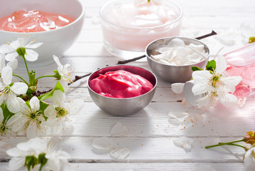 beauty products and cherry blossom on white wood table