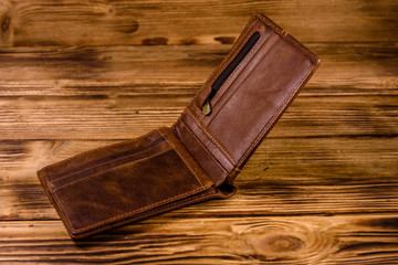 Opened brown leather wallet on wooden table