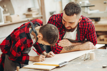 profession, carpentry, woodwork and family concept - carpentery masterclass for little children and their fathers to share basic knowledge of working with wood.