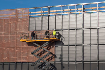 Men on scaffolding build an industrial building façade