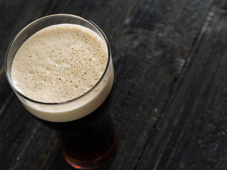Cold glass of dark stout beer on wooden table