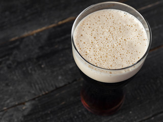 Pint of dark stout beer on wooden background