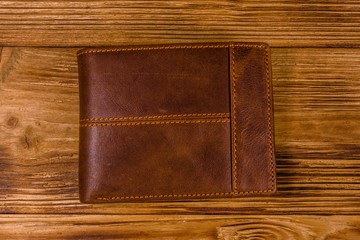 Closed brown leather wallet on wooden table. Top view