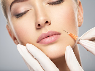 Woman getting cosmetic injection of botox in cheek