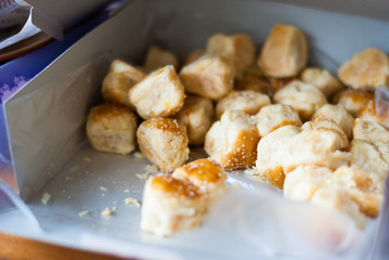 Small paper box is openning showing a lot of delicious golden brown baking dessert inside