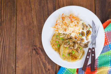 Rustic food concept. Fried potato pancakes with sauce and mushrooms on wooden table