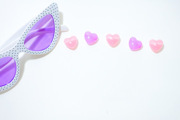 Colorful stones in heart shape and sunglasses on white background