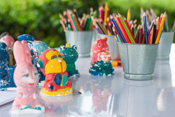 Sharp and blunt color pencils are put in bucket with plaster figure ready to be painted in art...