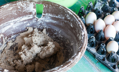 Fresh duck eggs placed beside salty white clay in making-salty eggs workshop for a kid