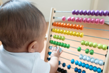 Asian baby playing colorful abacus toy defocusing on hand movement