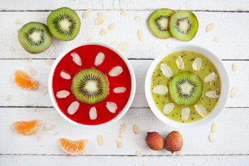 Smoohtie bowls z mrożonych truskawek i kiwi ozdobione owocami i płatkami migdałów