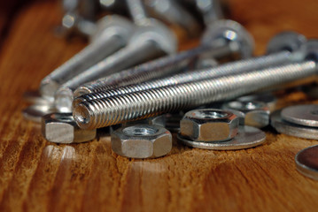 Fototapeta na wymiar Several long screws for home workshop on a wooden surface closeup. Shallow depth of field