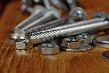 Several long screws for home workshop on a wooden surface closeup. Shallow depth of field