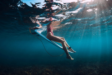 Young surf girl at surfboard underwater in ocean