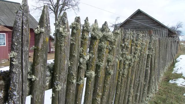 rickety fence with wicket door. Old ruined abandoned wooden house