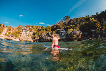 Attractive surfer girl with surfboard. Surfer sit at board in ocean.