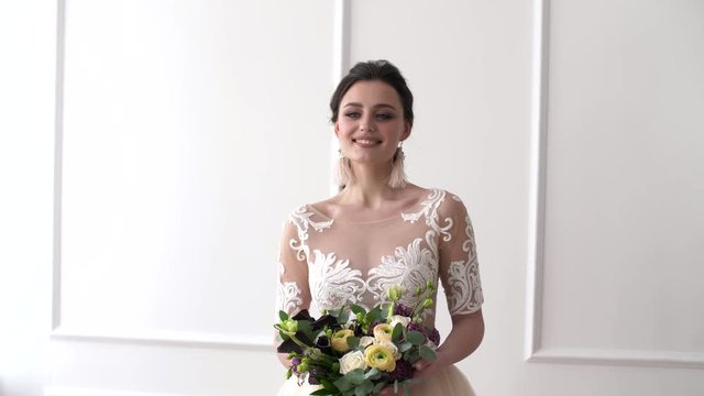 Portrait of a bride in wedding dress. Elegant brunette bride with flowers