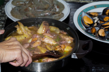 preparing delicious casserole of seafood and rice- paella a la marinera