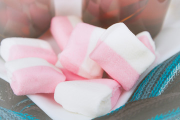 White-pink marshmallow on a plate with two cups of tea