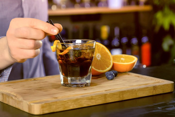 Barman prepare alcohol cocktail on bar counter, hands close-up.