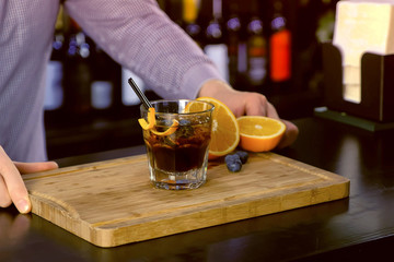 Barman prepare alcohol cocktail on bar counter, hands close-up.