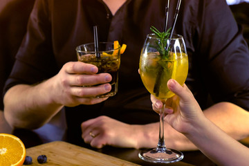 Man and woman in bar counter with alcohol cocktails. Hands close-up.