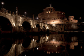 beautiful view of Castel Sant'Angelo and the bridge at night with reflections on the Tiber river....