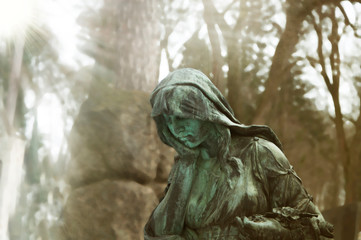 A sculpture of sad woman in grief. Virgin Mary bronze  statue (faith, suffering, death concept)