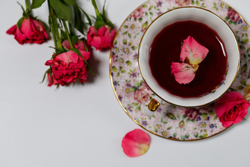 A cup of tea with a rose hip flower. Sunny spring evening. Therapeutic natural tea. Soft focus. 