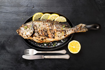 Tasty grilled fish dorado with  lemon on kitchen table.