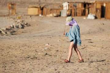 Boy tourist walks in a Bedouin village with cane sprigs in his hands