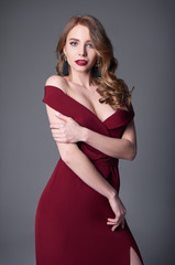 Studio fashion shot: portrait of smiling beautiful young woman in red dress