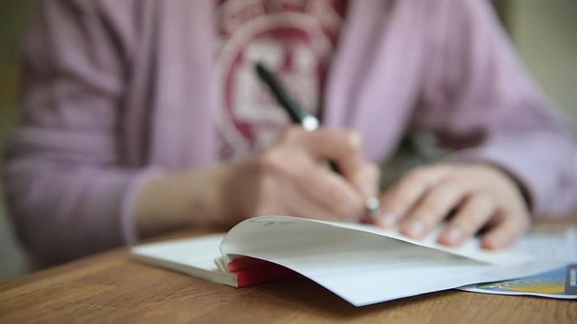 Side view a young business woman opening a checkbook filling a banking cheque check writingwith luxury fountain pen the requested data 